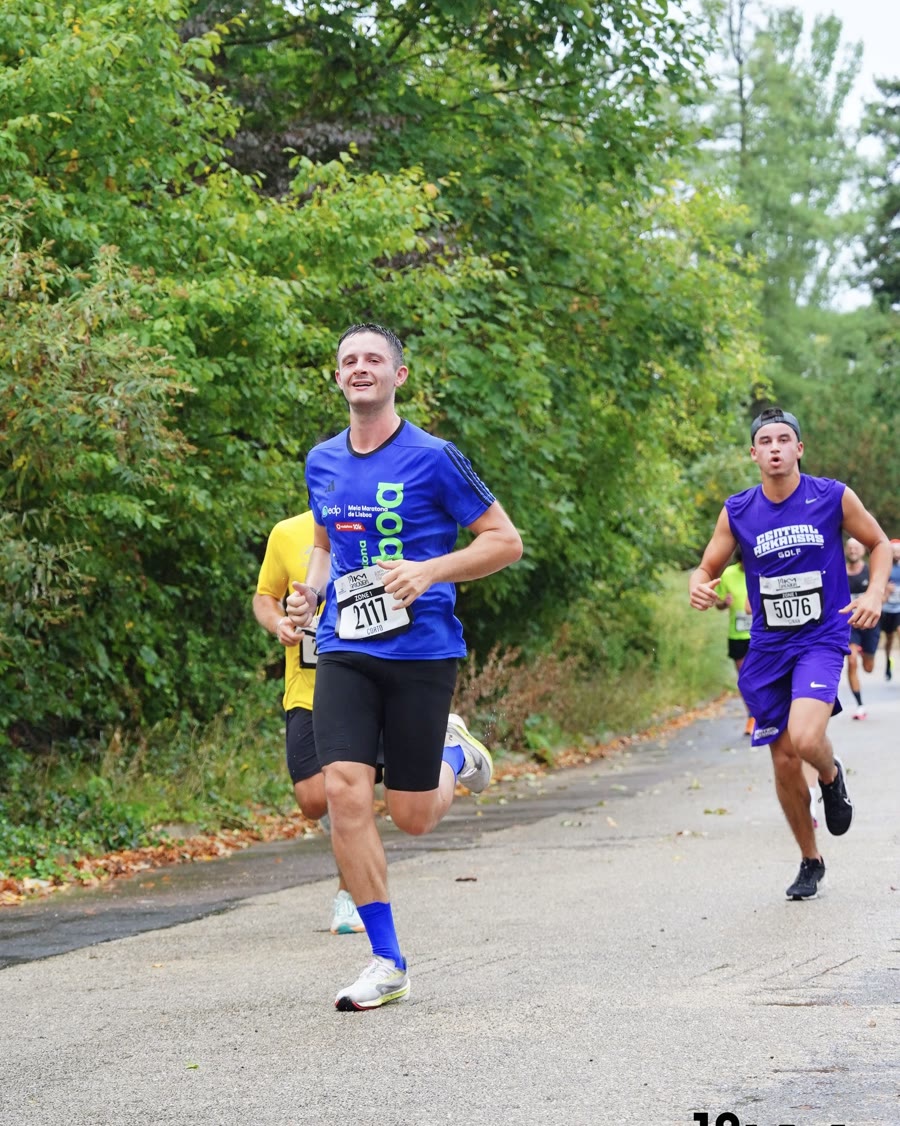 Corto Benzoni en course sur le 10 km du Trocadéro, maillot bleu, dans une allée bordée d'arbres.